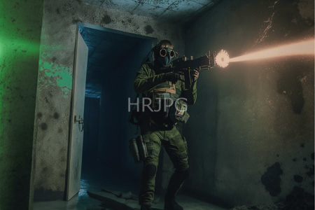 High Resolution: Armed soldier in green tactical gear and gas mask stands inside a dilapidated concrete room firing a rifle that emits bright orange muzzle flash download. | HRJPG.com